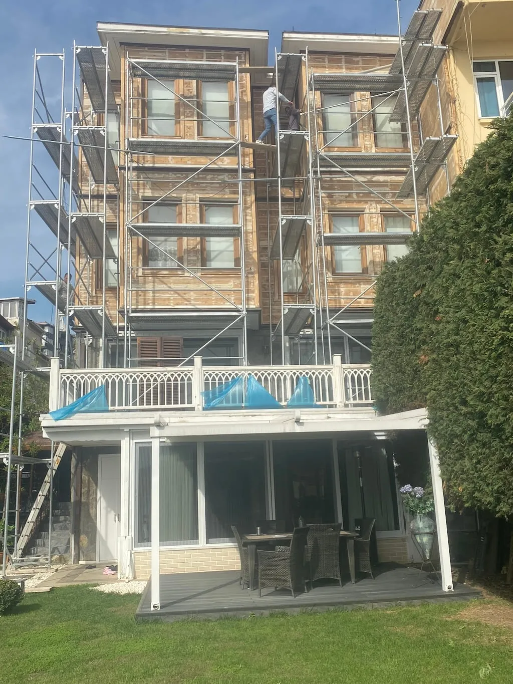 Ahşap köşkte dış cephe onarımı için raspa çalışması yapan usta