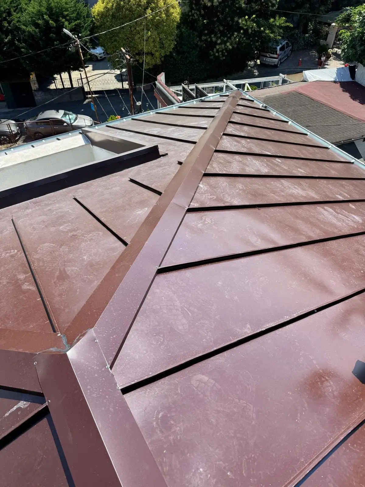 Bordo kenetli metal çatıda ışıklık boşluğunun çevresindeki kenar bükümü ve mahya detayı
