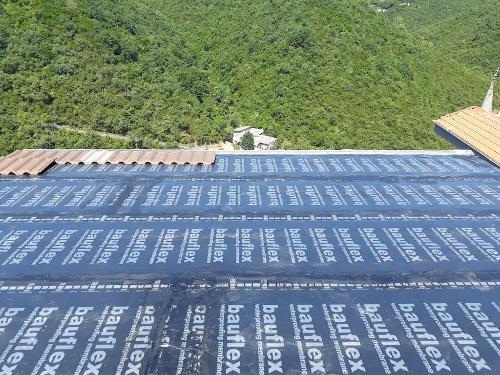 Su yalıtım membranı serilmiş eğimli çatıya metal kiremit döşenirken çekilmiş geniş açılı fotoğraf
