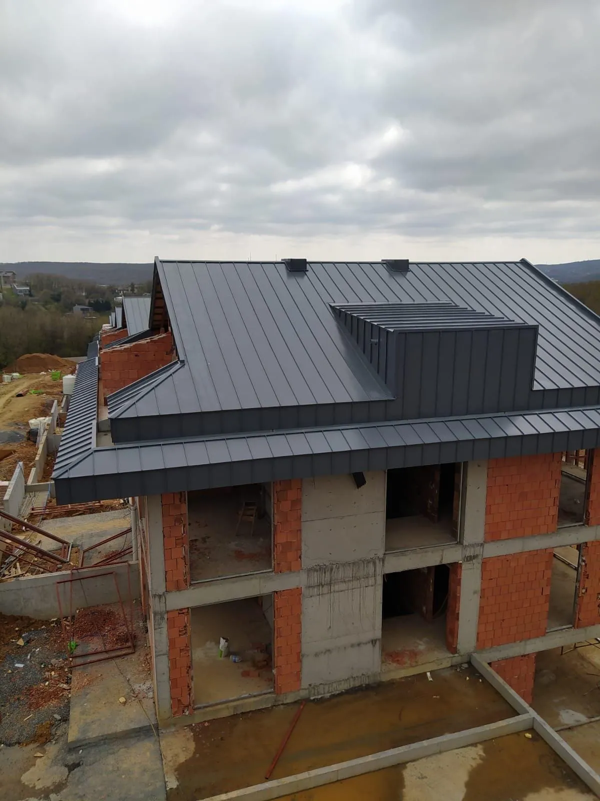 Yeni yapıda antrasit kenetli metal kaplama uygulanmış kırma çatı ve çatı çıkıntısı (dormer)